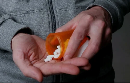 мужчина насыпает таблетки в руку